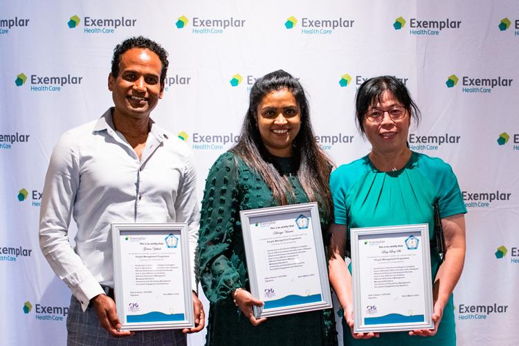 Three colleagues stood with certificates