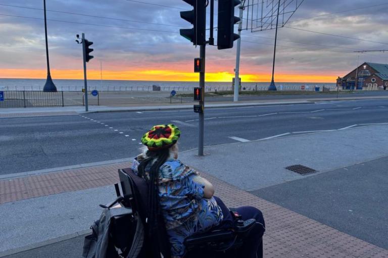 Male service user in wheelchair watching sunset on Blackpool beach