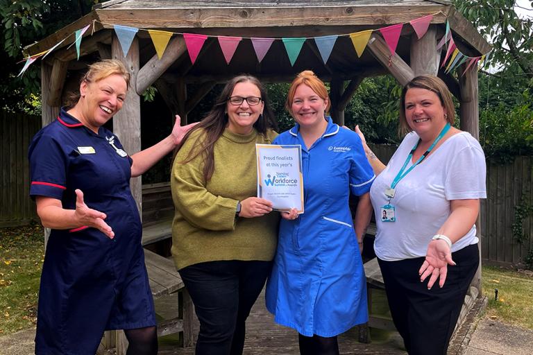 Four colleagues stood cheering outside, two with certificates