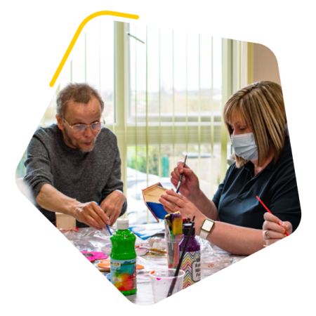 Photo of care home resident and Activities Coordinator doing arts and crafts